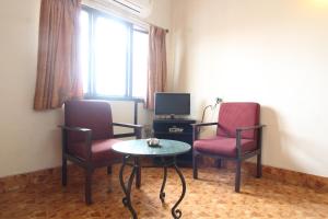 Zimmer mit 2 Stühlen, einem Tisch und einem TV in der Unterkunft Agarwal's Residency in Visakhapatnam