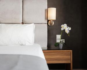 a bedroom with a bed and a table with a flower on it at Lacoba Hotel in Athens