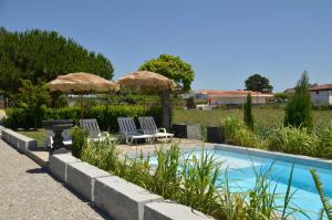 a swimming pool with two chairs and umbrellas at Abrigo do Moleiro in Ribeirão