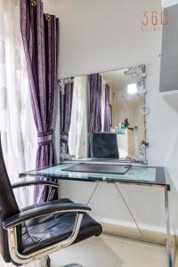 ナッシャーにあるCosy, fully equipped 1BR home with Private Balcony by 360 Estatesのガラス製デスク(椅子付)、ノートパソコン