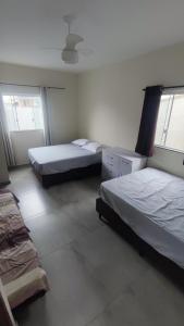 a bedroom with two beds and two windows at Sobrado com 3 quartos piscina 100m mar em matinhos in Matinhos