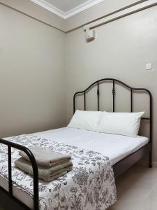 a bed with a black frame and white sheets and pillows at Seaview apartment in Kuala Terengganu