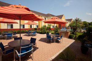 an outdoor patio with tables and chairs and umbrellas at TownePlace Suites by Marriott Lake Jackson Clute in Clute