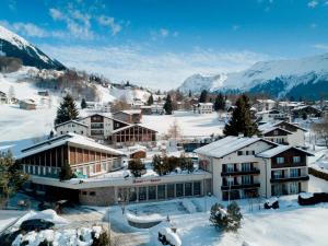 een stad in de sneeuw met bergen op de achtergrond bij Hotel Sport Klosters in Klosters