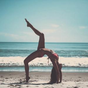 Una mujer haciendo un puesto de manos en la playa en OKU - soulful suites, en Casale Marittimo