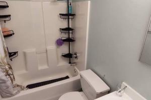 a bathroom with a white toilet and a bath tub at Private room in 4 bedroom Ground Apartment near Subway in Brooklyn