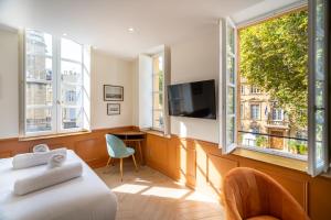 Habitación con 2 camas, TV y ventanas. en La Réserve de Salon de Provence, en Salon-de-Provence