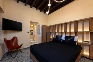 a bedroom with a black bed and a chair at Townhall Apartment in Symi +16 photos