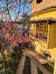 uma casa amarela com flores cor-de-rosa ao lado em Pousada Mirante Pôr do Sol em Maricá