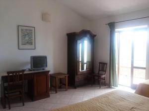 sypialnia z łóżkiem, telewizorem i biurkiem w obiekcie Agriturismo La Mancosa w mieście Pollica