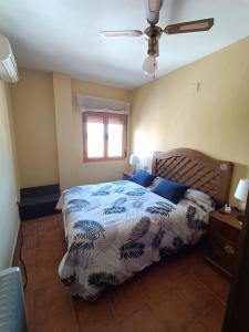 a bedroom with a bed with a blue comforter and a window at El rincon de los enebros in Ruidera