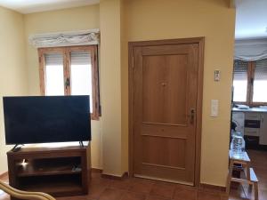 a living room with a television and a door at El rincon de los enebros in Ruidera