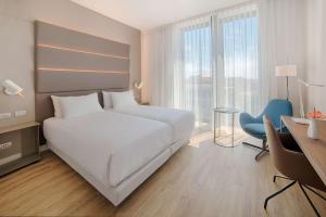 una camera d'albergo con letto bianco, scrivania e finestra di Avani Rio Novo Venice Hotel - previously NH Venezia Rio Novo a Venezia