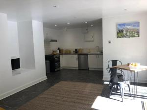 a kitchen with a table and chairs in a room at Sharp Tor Riverside Studio Apartment in Plymouth