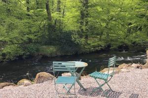 two chairs and a table next to a river at Sharp Tor Riverside Studio Apartment in Plymouth