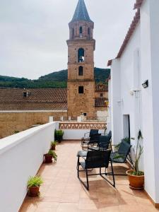 Un balcón con sillas y una torre de reloj. en Apartamentos rurales, La Casa de Baltasar, en Fondón
