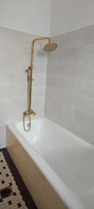 eine weiße Badewanne mit einem goldenen Wasserhahn im Bad in der Unterkunft Luxury Apartment 3 Rooms in Bukarest