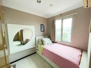 een kleine slaapkamer met een bed en een spiegel bij Galeri Ciumbuleuit Apartment 1 2BR 1BA - code 12B in Bandung