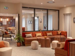 a living room with a couch and tables and chairs at Novotel Orléans Centre Gare in Orléans