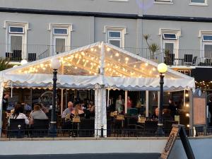 un grupo de personas sentadas en un restaurante bajo una tienda blanca en Smiths Hotel, en Weston-super-Mare