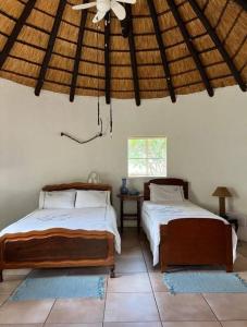 a bedroom with two beds and a ceiling fan at Bosveldsig Cottages in Modimolle