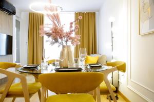 a dining room table with yellow chairs and a vase with flowers at Supernova Royal Residence in Novi Sad
