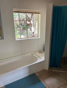 baño con bañera y ventana en Bosveldsig Cottages, en Modimolle