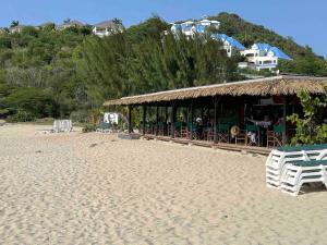 a beach with a hut with chairs and tables on it at Friar's beach - Luxurious unit by the beach in Saint Martin