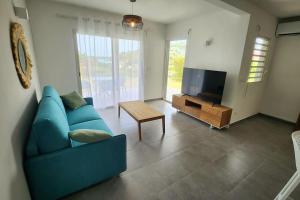 a living room with a blue couch and a tv at Friar's beach - Luxurious unit by the beach in Saint Martin