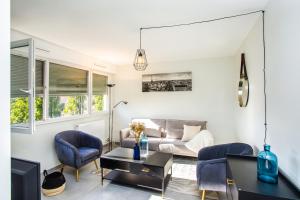 een woonkamer met een bank en stoelen en een tv bij Appartement neuf moderne à louer in Ferney-Voltaire