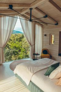a bedroom with a large bed with a large window at Domaine de Casanghjulina in Porto-Vecchio