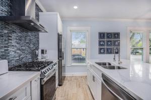 a white kitchen with a stove and a sink at Luxury Designer Villa by the Beach Bright Beautiful Brand New in Galveston