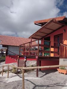 ein rotes Haus mit einem Zaun davor in der Unterkunft Chalé Adventure in Serra de São Bento