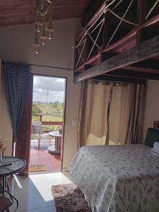 a bedroom with a bed and a view of a patio at Chalé Adventure in Serra de São Bento