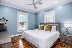 a blue bedroom with a bed and two windows at Luxury Designer Villa by the Beach Bright Beautiful Brand New in Galveston