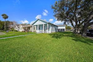 a house with a green lawn in front of it at Luxury Designer Villa by the Beach Bright Beautiful Brand New in Galveston