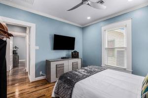 a blue bedroom with a bed and a flat screen tv at Luxury Designer Villa by the Beach Bright Beautiful Brand New in Galveston
