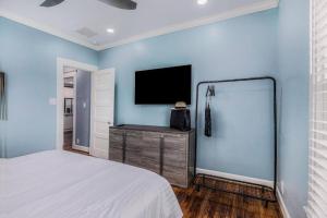 a bedroom with a bed and a tv on a blue wall at Luxury Designer Villa by the Beach Bright Beautiful Brand New in Galveston