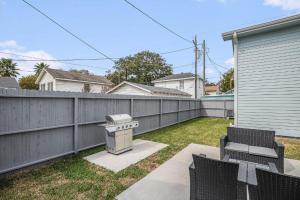a backyard with a fence and chairs and a grill at Luxury Designer Villa by the Beach Bright Beautiful Brand New in Galveston