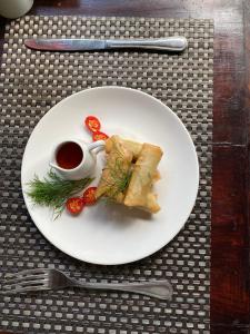 a white plate with food and a cup of sauce at Crystal Bay Villa in Nusa Penida