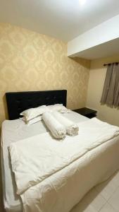 ein Schlafzimmer mit einem weißen Bett mit weißer Bettwäsche und Kissen in der Unterkunft Puncak Bukit Golf Apartemen in Surabaya