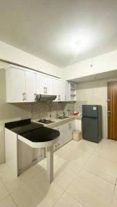 eine Küche mit weißen Schränken und einem schwarzen Kühlschrank in der Unterkunft Puncak Bukit Golf Apartemen in Surabaya