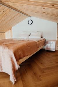 a bed in a room with a wooden ceiling at Osada Jaćwingów in Gołdap +41 photos