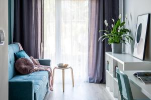 ein Wohnzimmer mit einem blauen Sofa und einem Fenster in der Unterkunft ADLER Studio - prywatny taras przy pokoju, dostęp na kod- BEZPŁATNY PARKING in Łódź