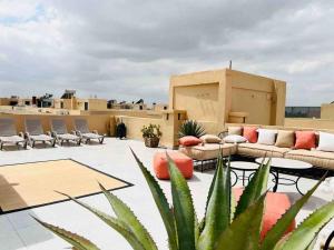 een dakterras met banken en tafels in een gebouw bij Magnifique villa avec piscine au cœur des palmiers in Marrakesh