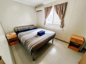 a bedroom with a bed with a blue bag on it at Karratha Village Workforce Accommodation in Karratha