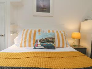 a bed with a yellow blanket and a pillow on it at Mackerel Sky in Marazion
