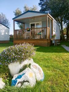 a tiny house with a large deck and flowers in the yard at KNAUS Campingpark Eckwarderhörne in Eckwarderhörne