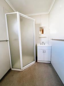 a bathroom with a glass shower door and a sink at Karratha Village Workforce Accommodation in Karratha