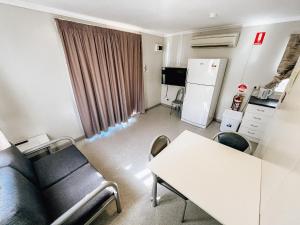a living room with a couch and a table and a refrigerator at Karratha Village Workforce Accommodation in Karratha